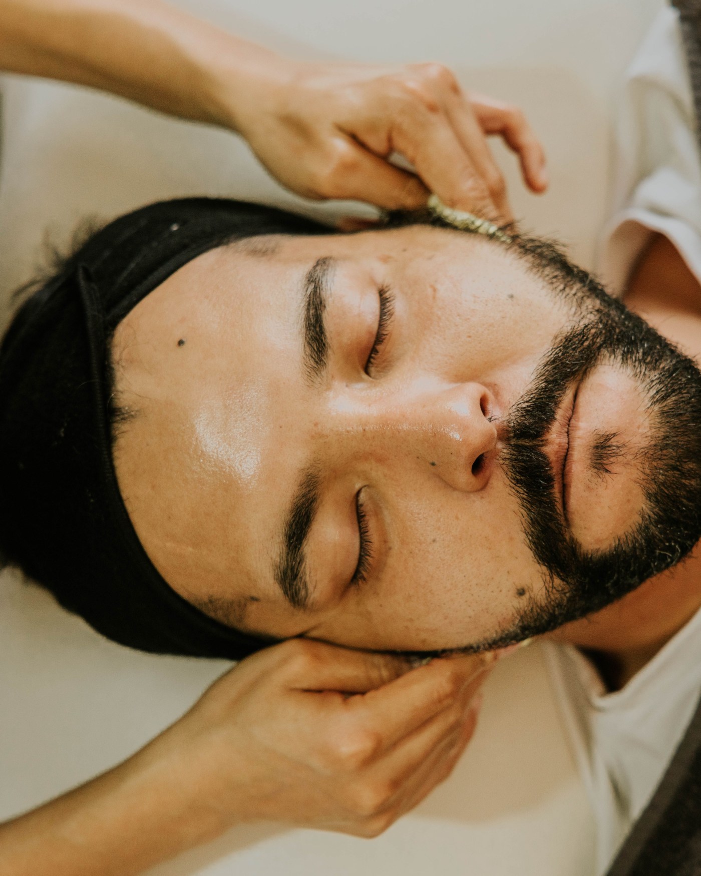 Un hombre recibe un masaje facial con los ojos cerrados